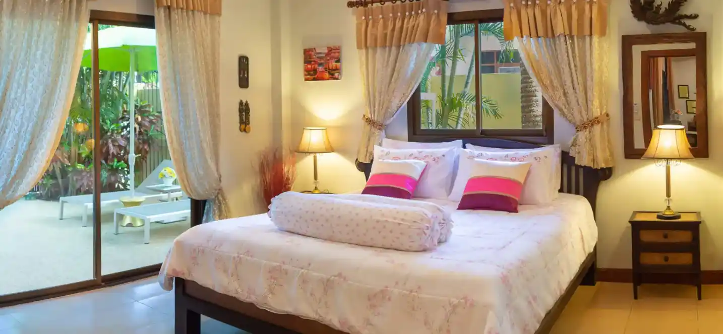 Coral Island Villa master bedroom with curtained windows and decorative Thai artwork